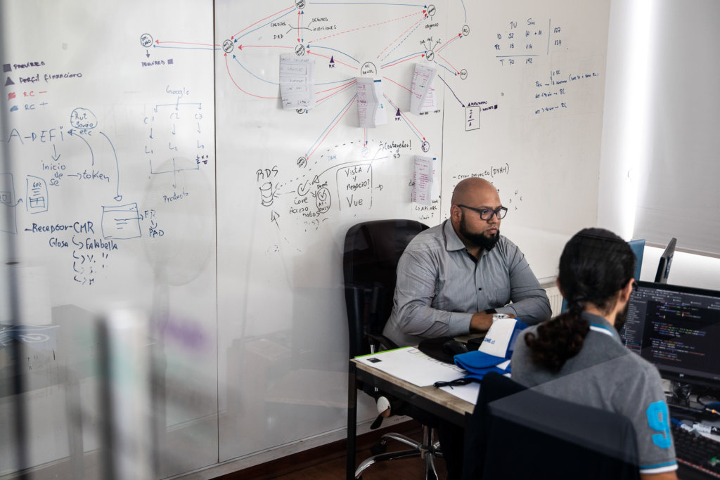 Nel sits at his computer in front of a white board covered in data