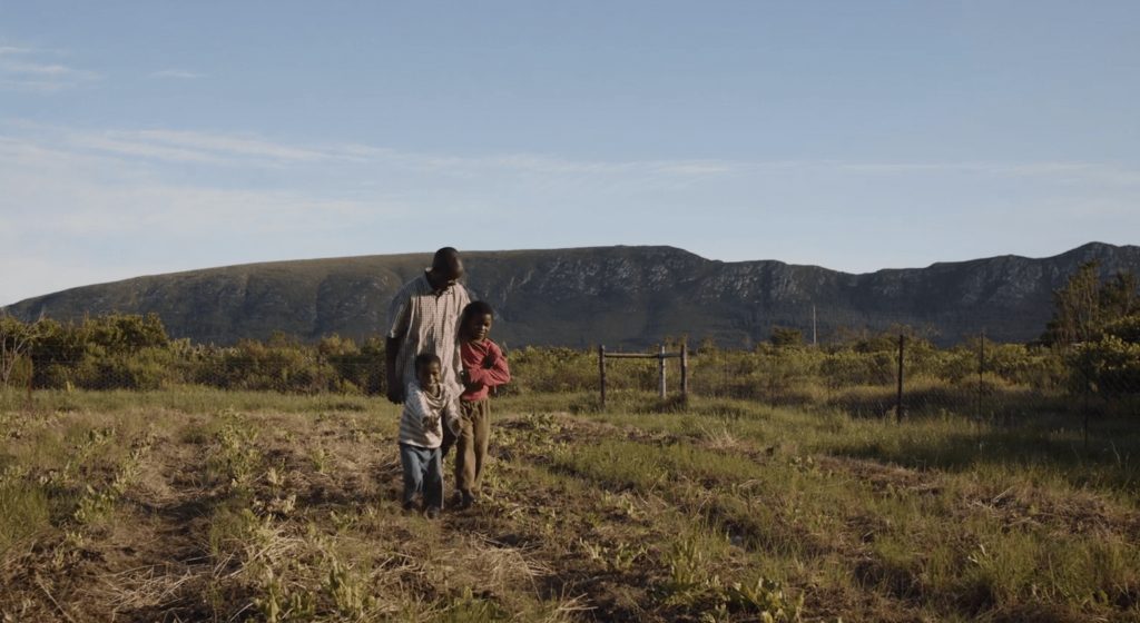 A farmer client walks on a field with his children