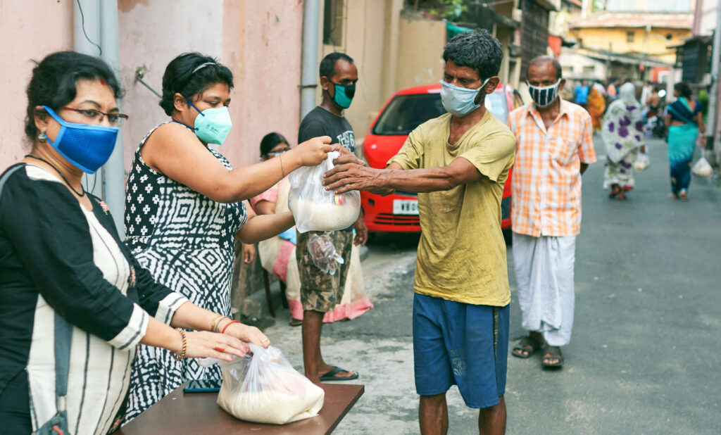 Civic volunteers responding to COVID-19 hand out groceries in Kolkata, India.