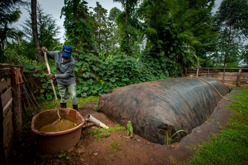 Andrew Kipkirui feeds waste into a small biodigester on his farm.