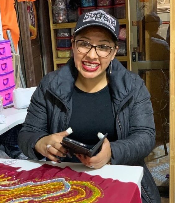 Lourdes, a BancoSol customer, shows the Accion and BancoSol team the applications she uses to design intricate patterns on fabric. 