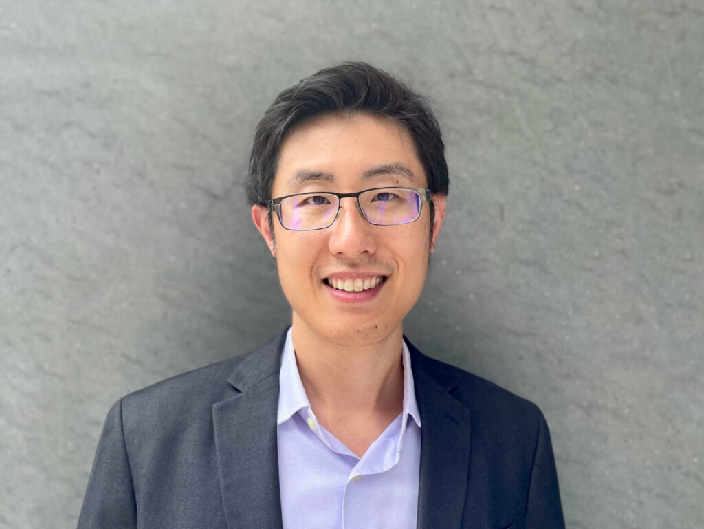 a headshot in front of a gray wall