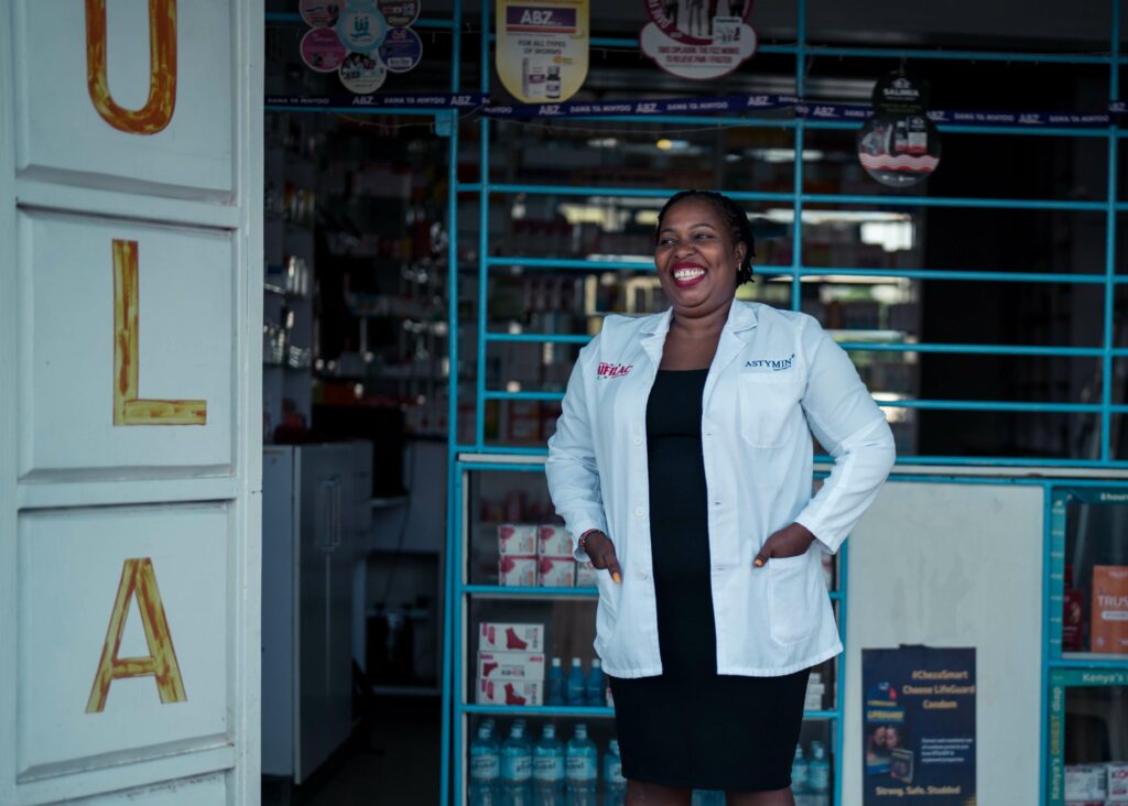 A smiling Serah stands in front of her pharmacy