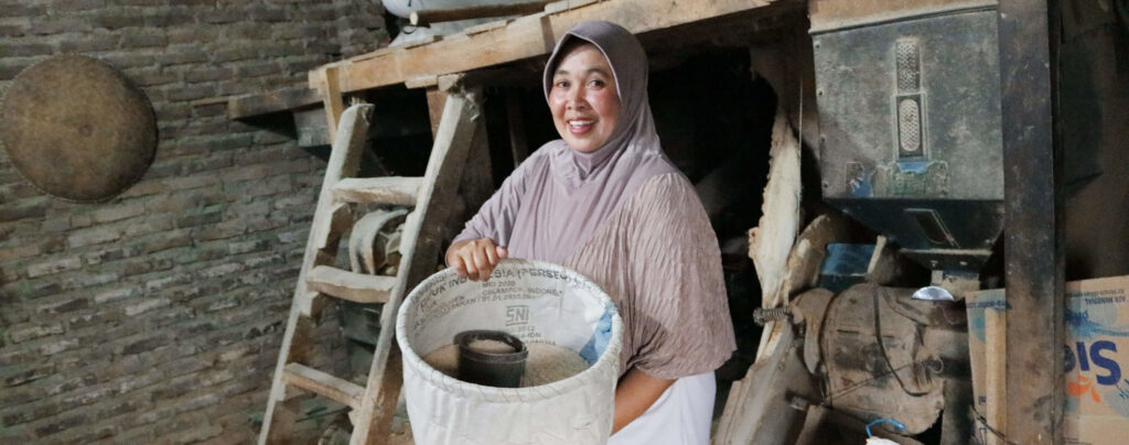 Ibu Oom, Bina Artha Ventura client, standing in her rice mill in West Java