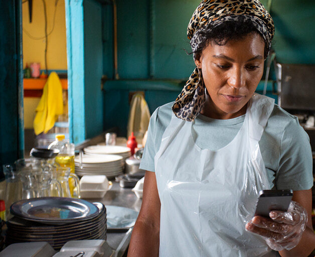 Restaurant worker checks her phone for an online order.