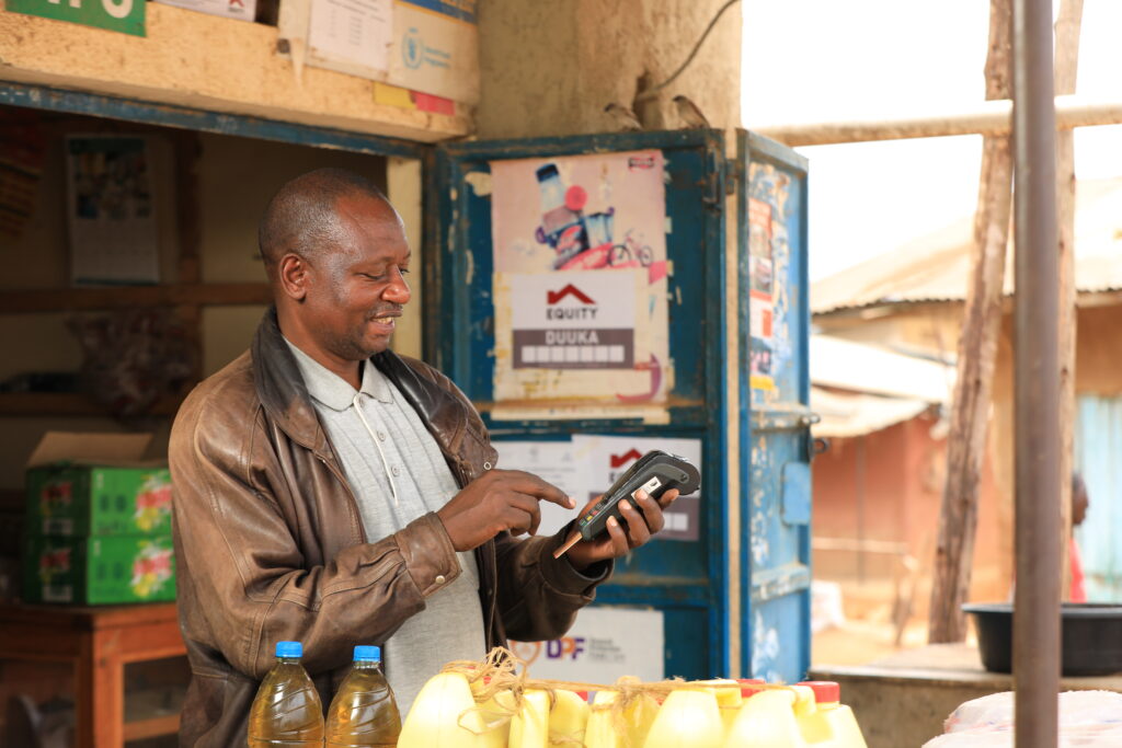 A small business owner and Accion MSME client, Havugimana Boneventure, uses a payments device at his shop in Uganda