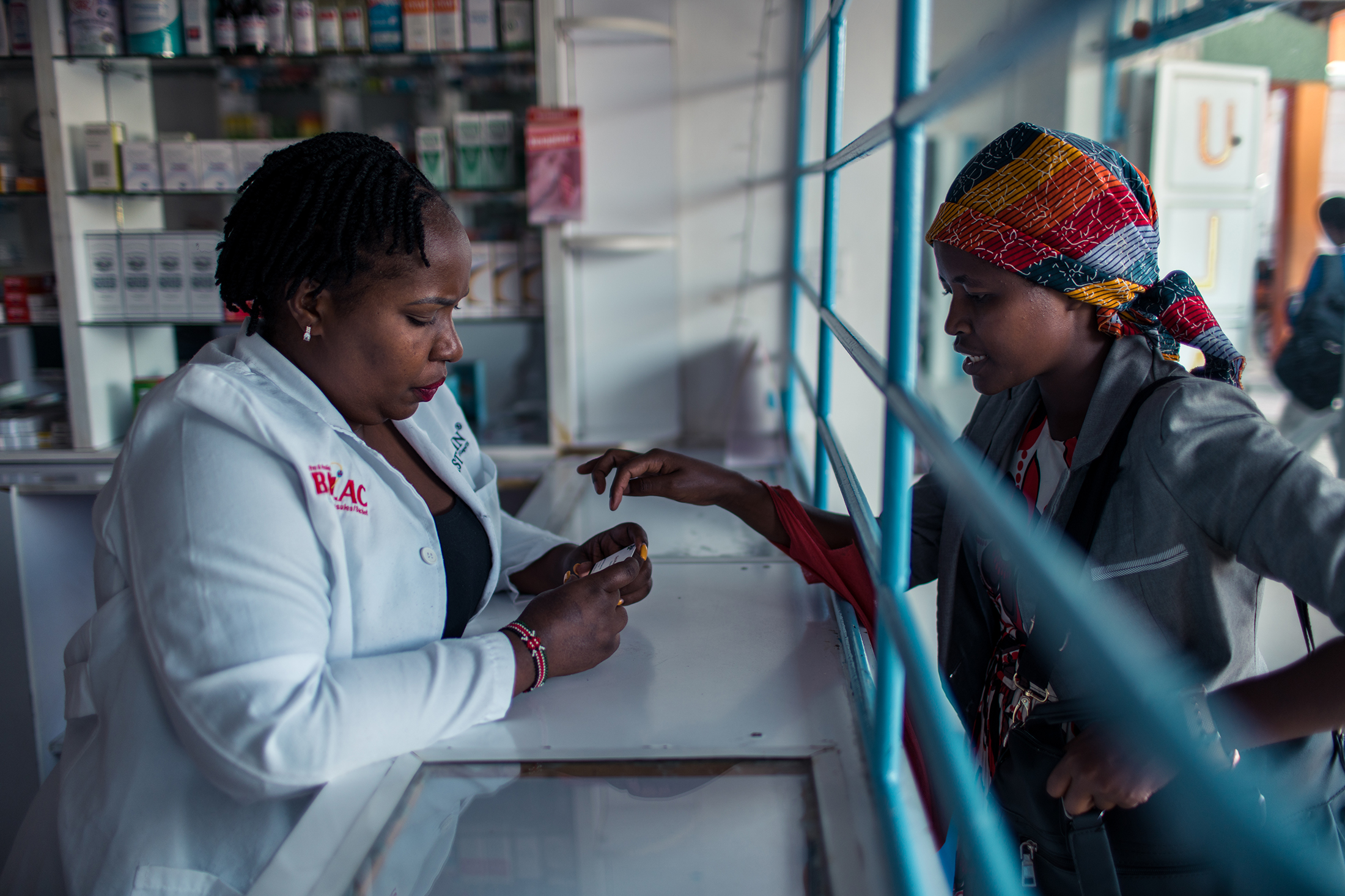 Serah assists a customer at her pharmacy in Nairobi, Kenya