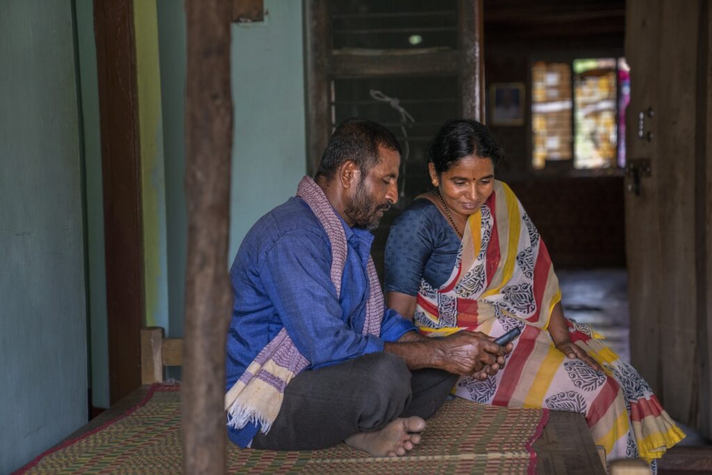 A couple sitting on the floor, looking at the phone