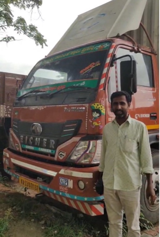 Narasimharaju standing next to a brown Eicher goods carrier truck used for milk transportation.