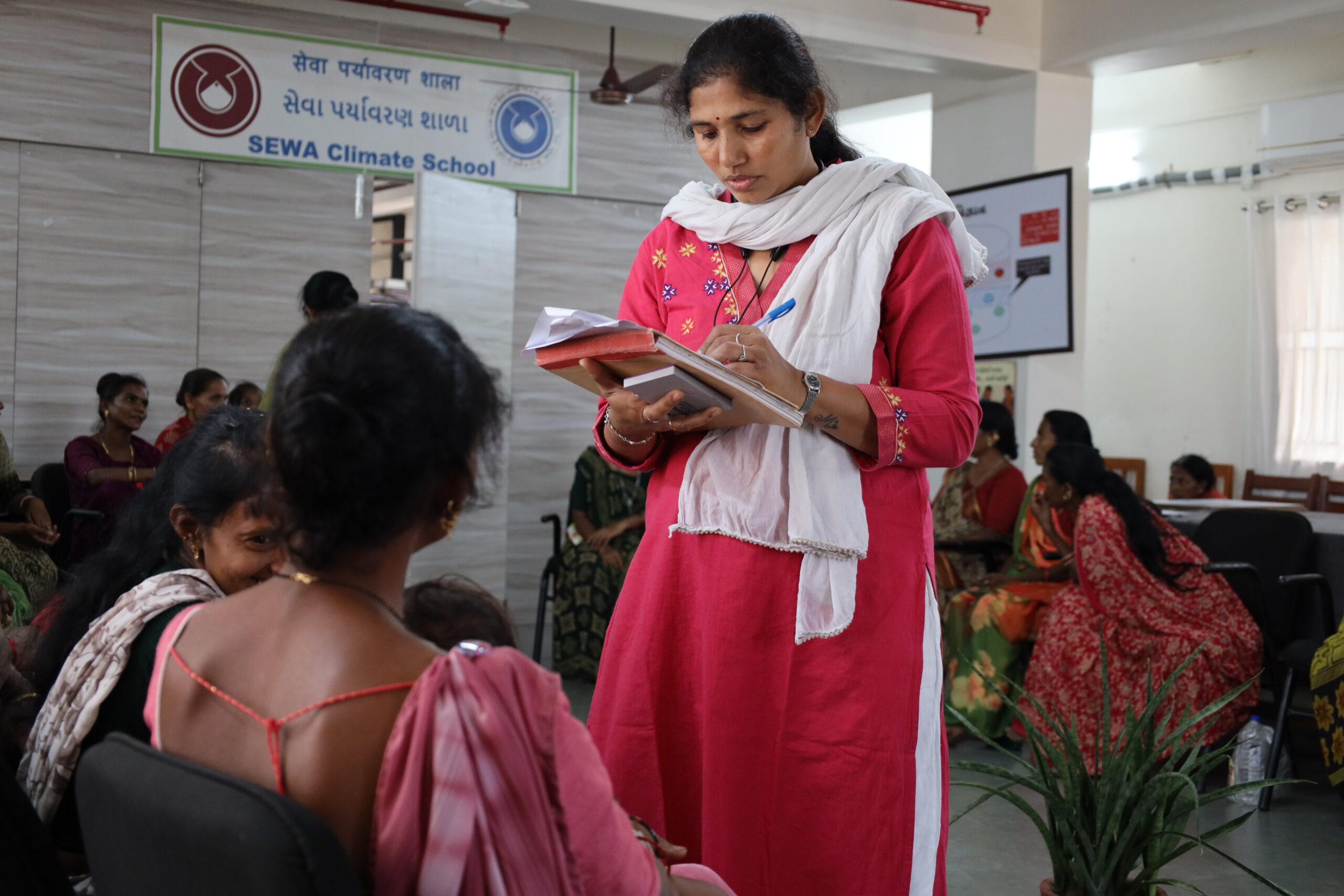 Woman stands in the middle of a group and takes note